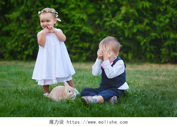 在草地上和兔子玩耍的小孩little boy with the girl and rabbit playing in the grass
